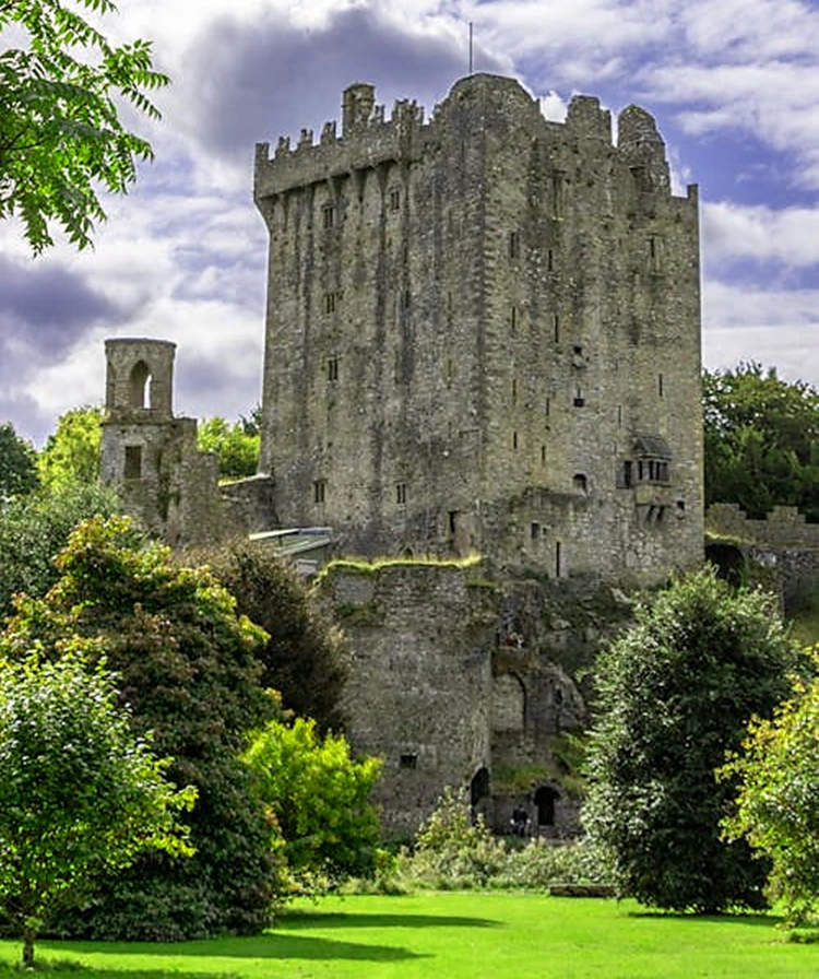 Main tower at Blarney Castle with gardens and trees in foreground
