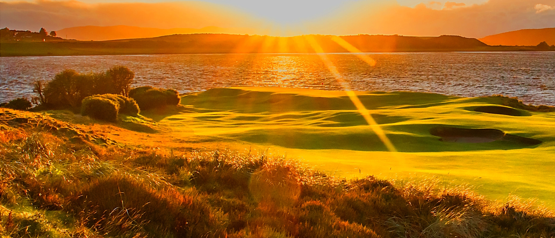 Castle Stuart 3rd hole with a sunburst over the green and Moray Firth
