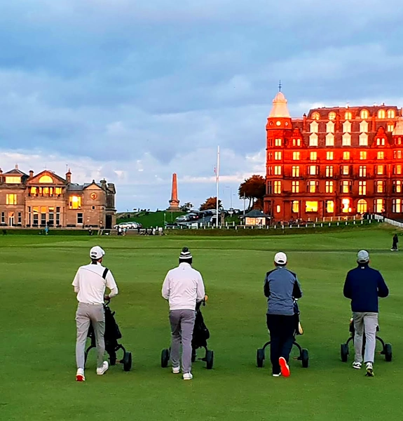 fourball walking up the 18th at St Andrews pushing golf trolleys in formation