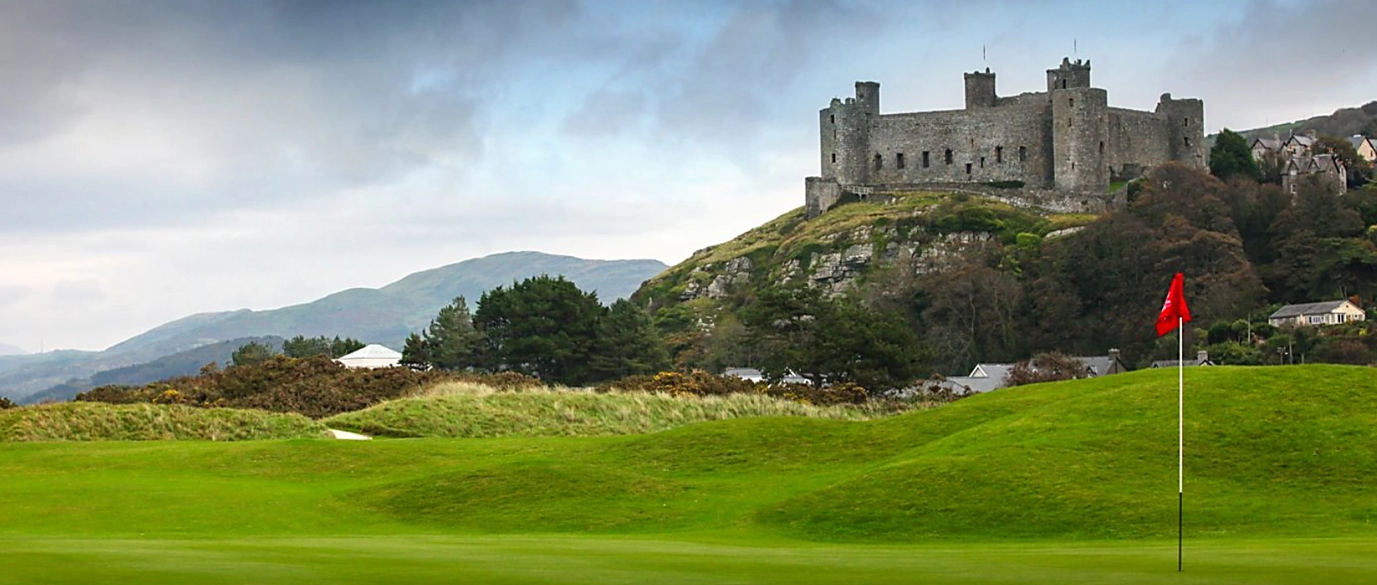 Royal St Davids green with flag in foreground, Harlech Castle in the background