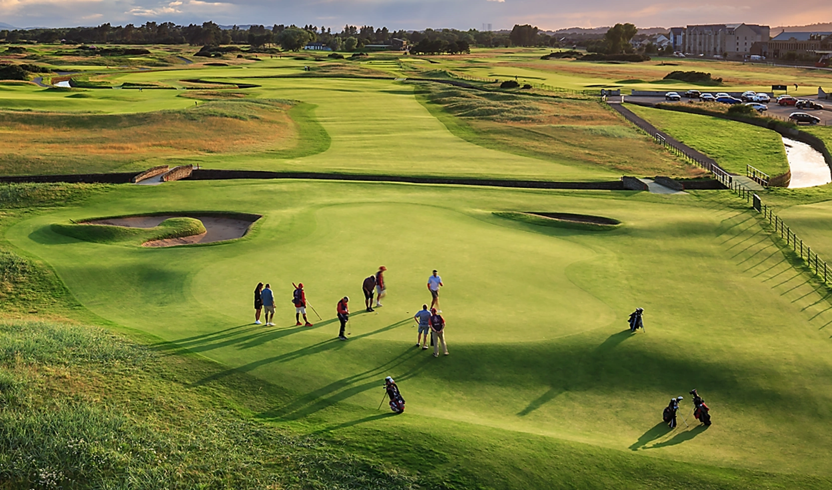 Looking down over the 18th green at Carnoustie at a party of golfers finishing off with the fairway and Barry burn in the background